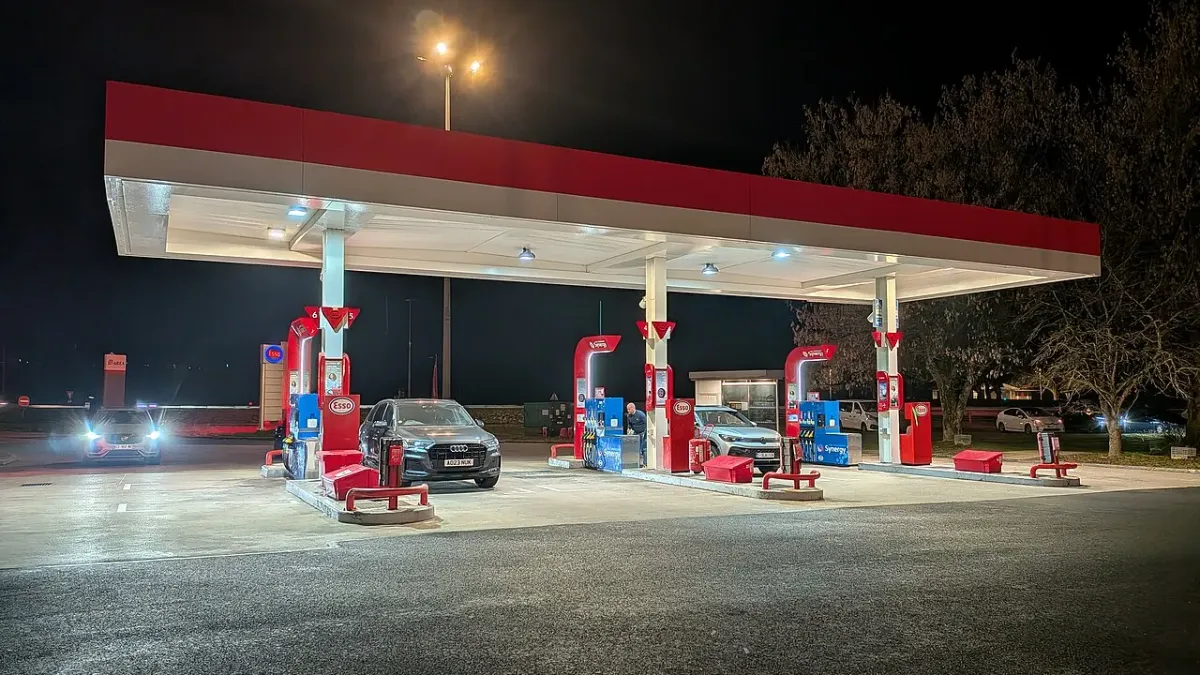 Station-service Esso de l'aire du Guiers sur l'A43, de nuit, avec un automobiliste en train de faire le plein