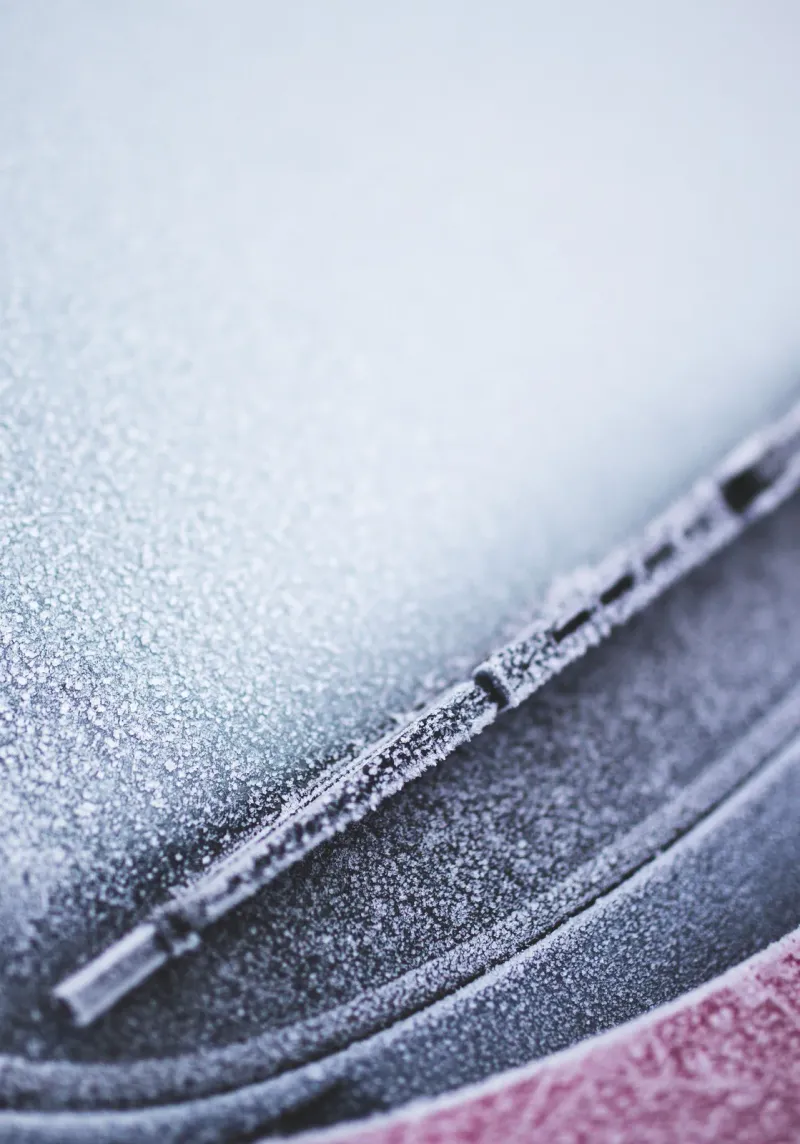 Voiture givrée démarrant tôt le matin en hiver, pare-brise couvert de givre