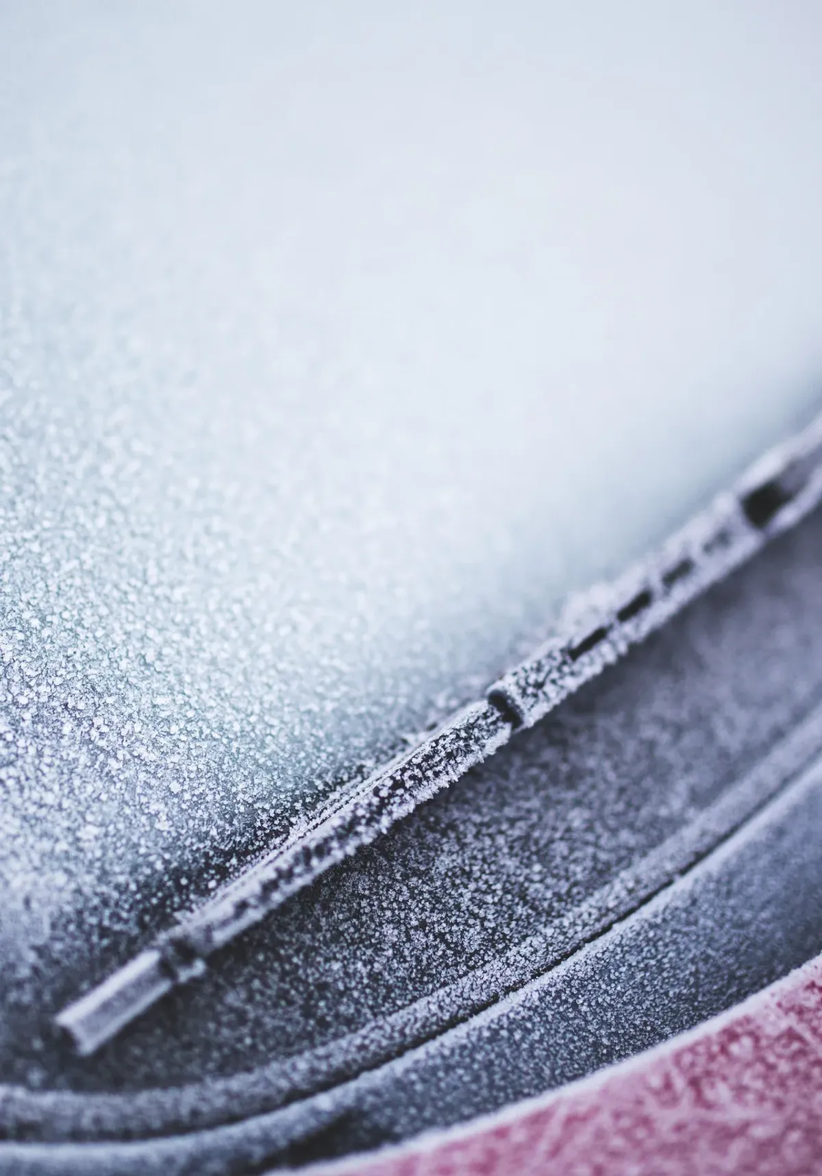 Voiture givrée démarrant tôt le matin en hiver, pare-brise couvert de givre