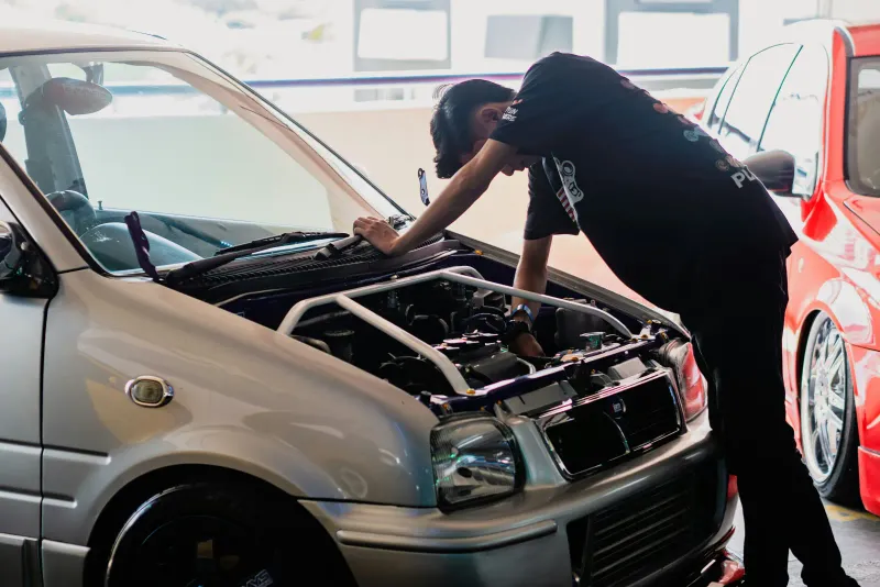 Mécanicien vérifiant le moteur d'une voiture, capot ouvert, avant le contrôle technique
