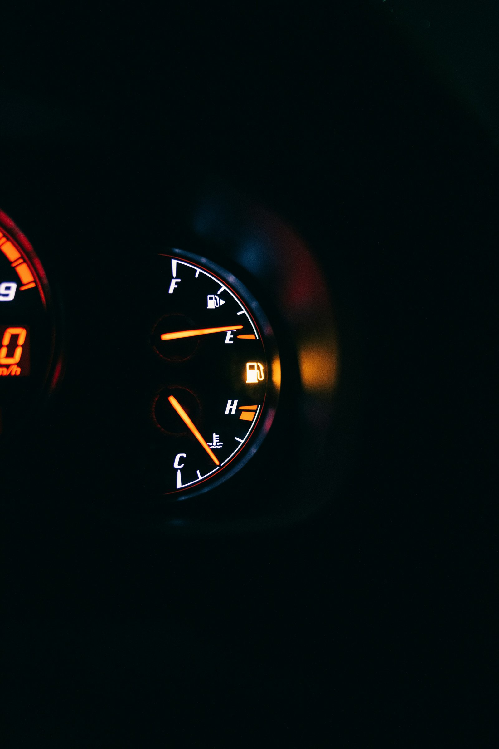 Gros plan sur la jauge à carburant d'un tableau de bord, aiguille sur E et voyant de réserve allumé en orange